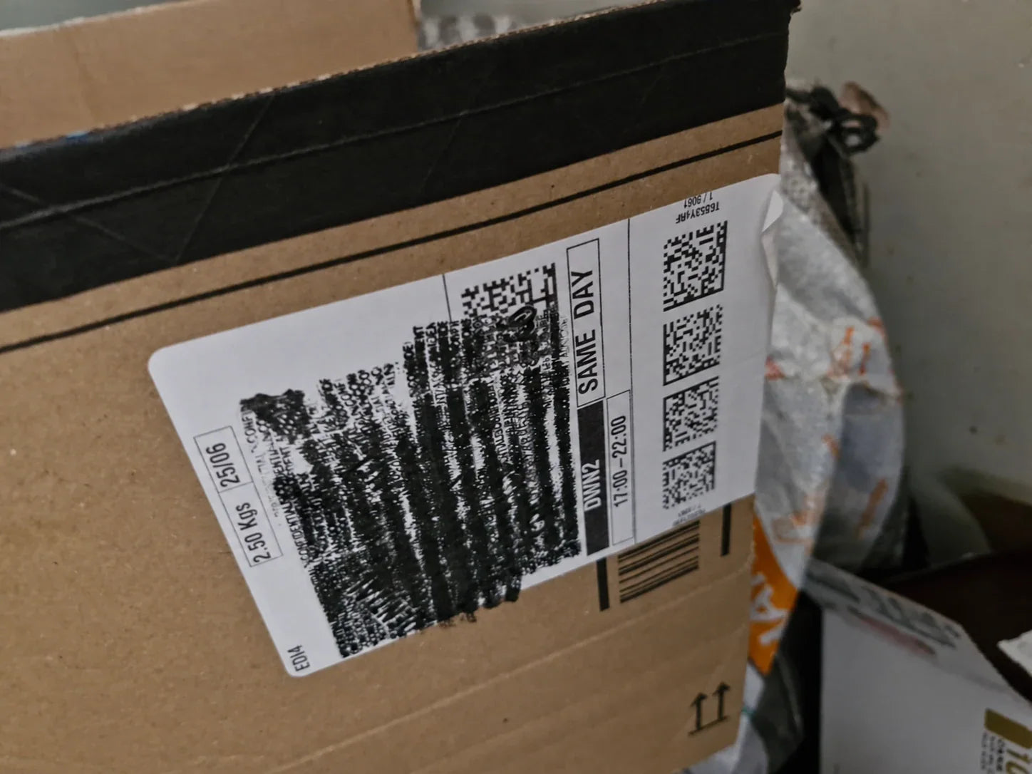 A cardboard parcel with a dense black privacy pattern rolled over the address label
