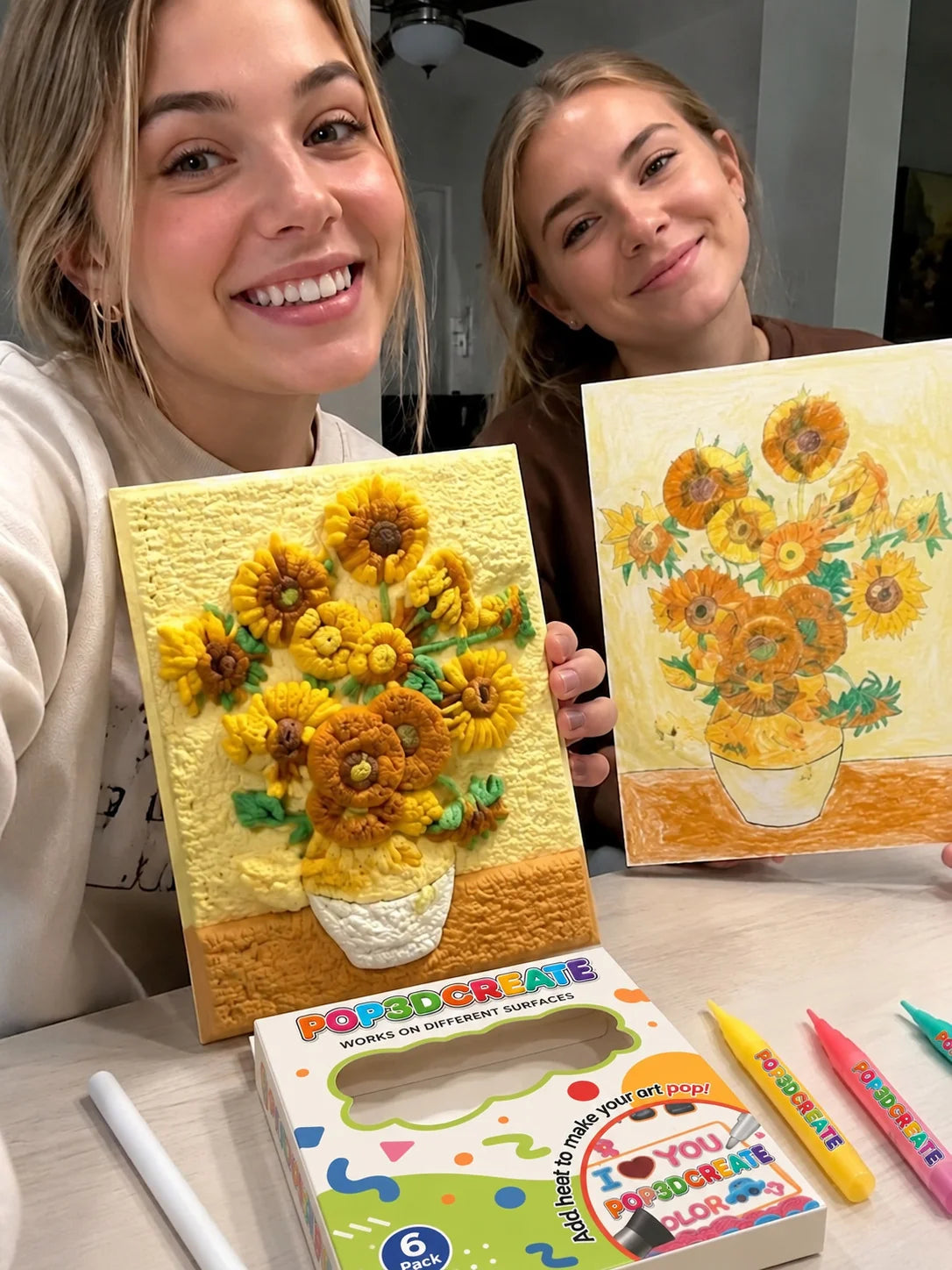 Two customers displaying handmade textured sunflower paintings.